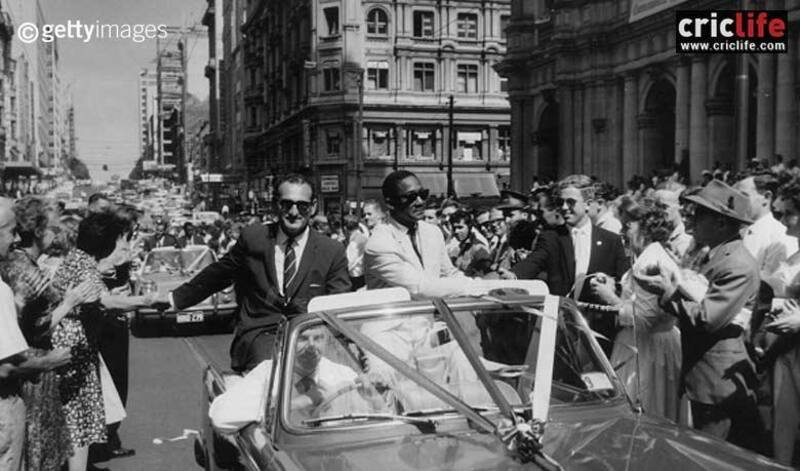 Gerry Gomez (left) and Sir Frank Worrell are cheered by the people of Melbourne lined up in the streets to bid farewell to the 1960-61 West Indies team at the end of their series against Australia. 