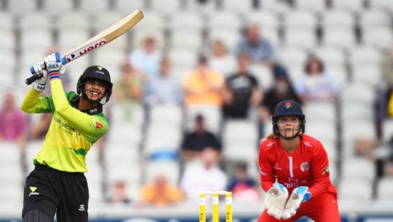 Smriti Mandhana hits one down the ground as Lancashire Thunder wicketkeeper Eleanor Threlkeld looks on © Getty Images